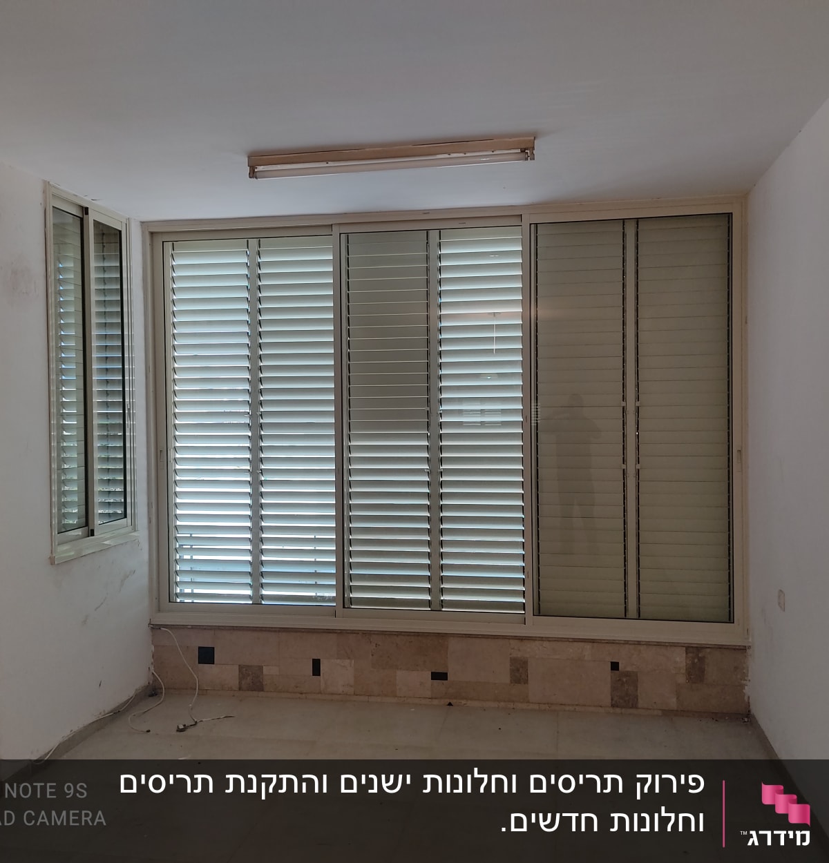 תריסי אלומיניום בחלון גדול בחדר ריק